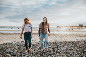 Two friends walking on the beach wearing Nöz colorful sunscreen